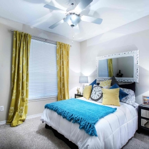 Wide angle view of bedroom in 2 bedroom model home with ceiling fan and transitional furniture